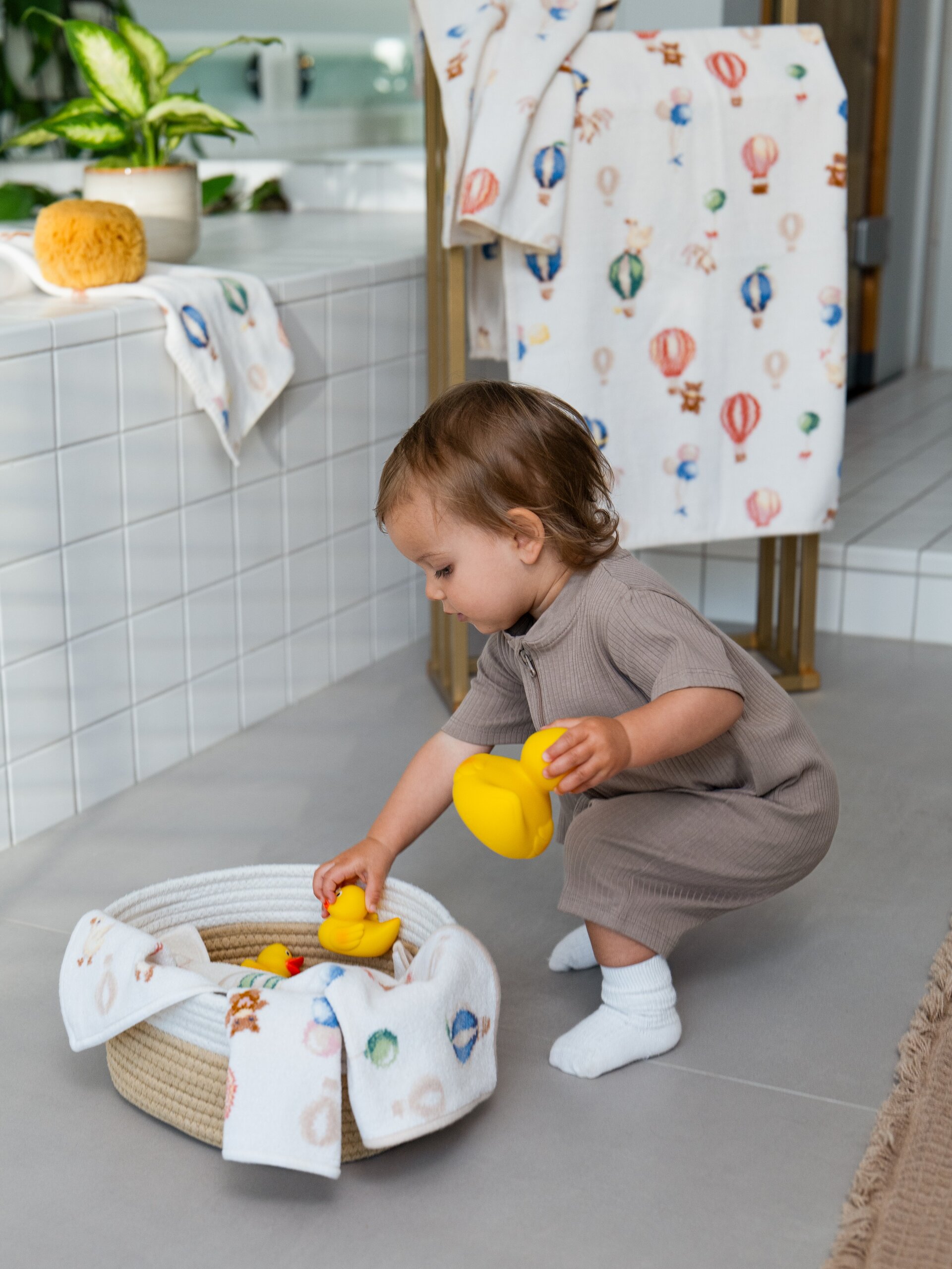 Lifestyle-Aufnahme des FEILER DREAMY BALLOONS Kinder-Handtuchs, Größe 37 × 50 cm, aus Original FEILER-Chenille mit einem Model und einer Spielente.