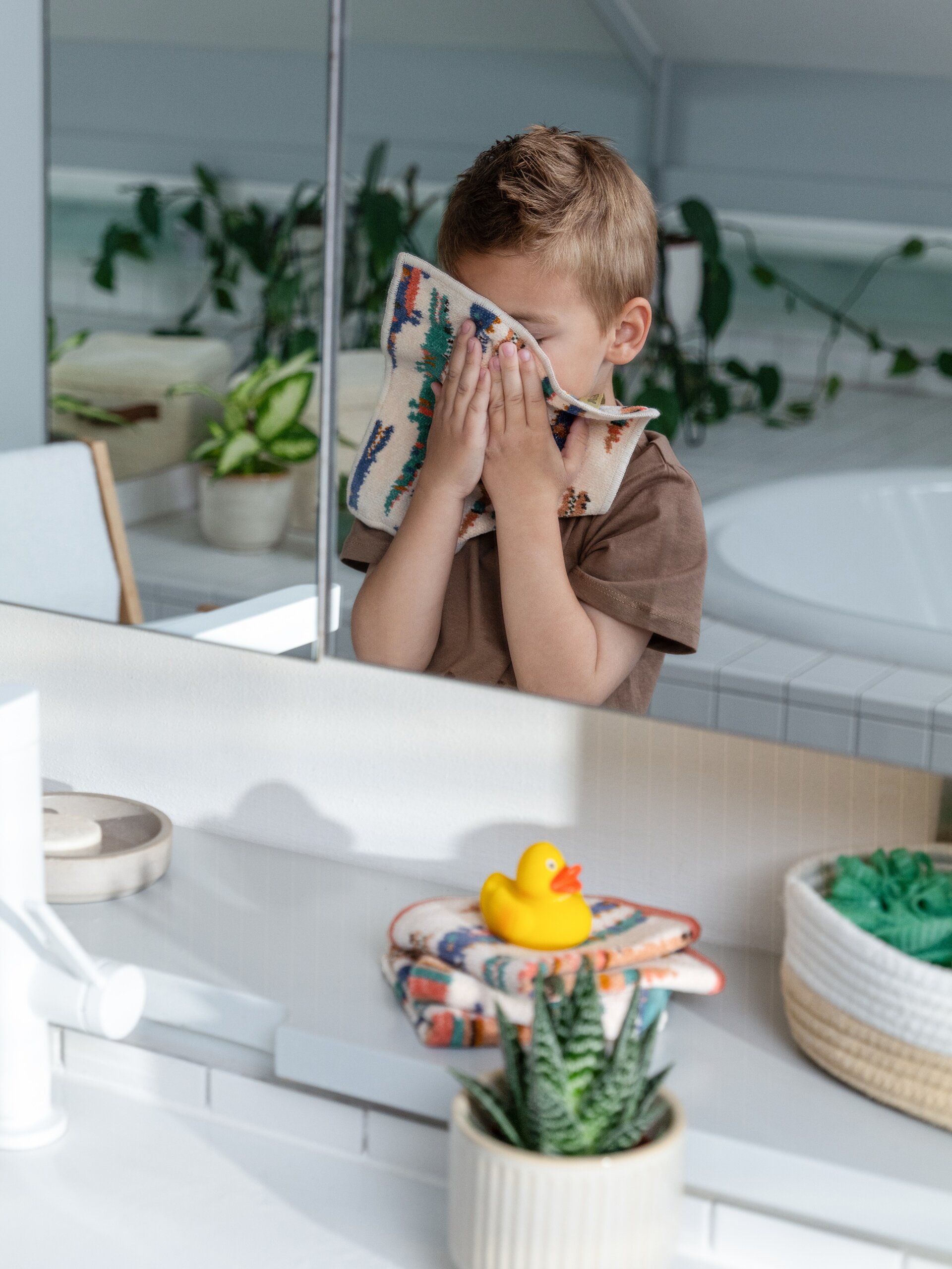 Lifestyle-Aufnahme mit FEILER KROKO Kinder-Handtuch und Pflegetüchern aus Original FEILER-Chenille beim Abtrocknen des Gesichts.