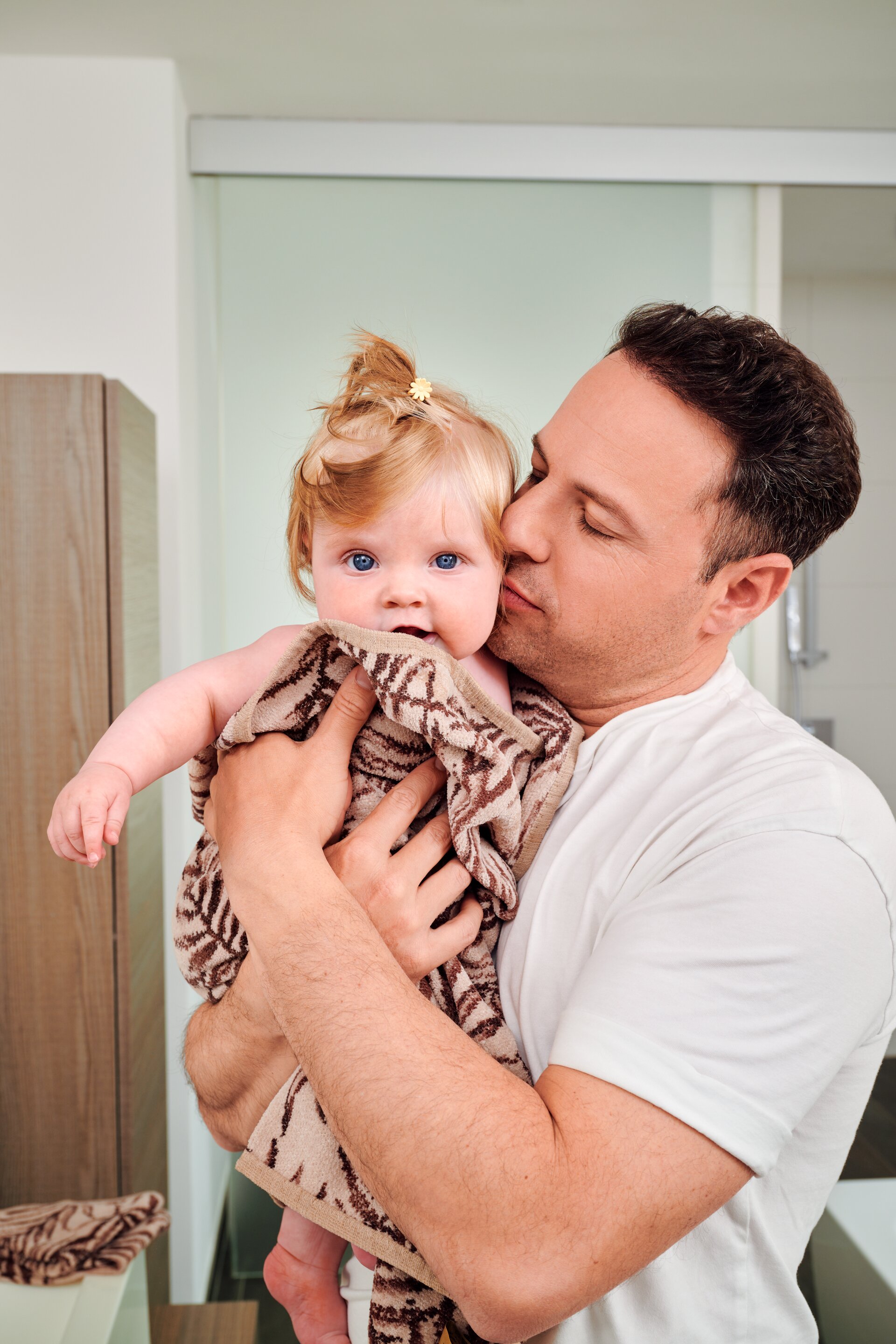 Lifestyle image of a father with FEILER DESERT PALMS bath textiles, made from soft Original FEILER chenille in Germany.
