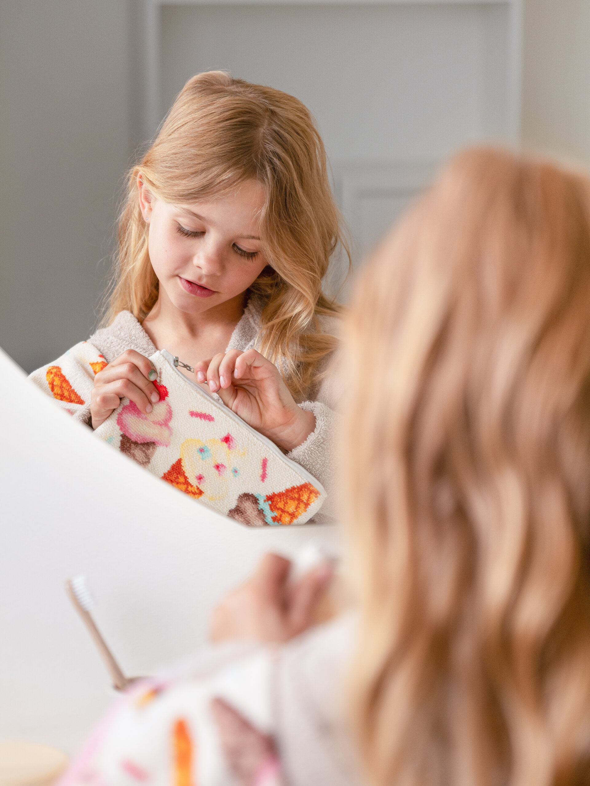 Kind mit Chenille-Textil am Spiegel – Luxuriöses FEILER Handtuch der Kollektion SWEET SPRINKLES als Lifestyleaufnahme aus Original FEILER-Chenille, Made in Germany.