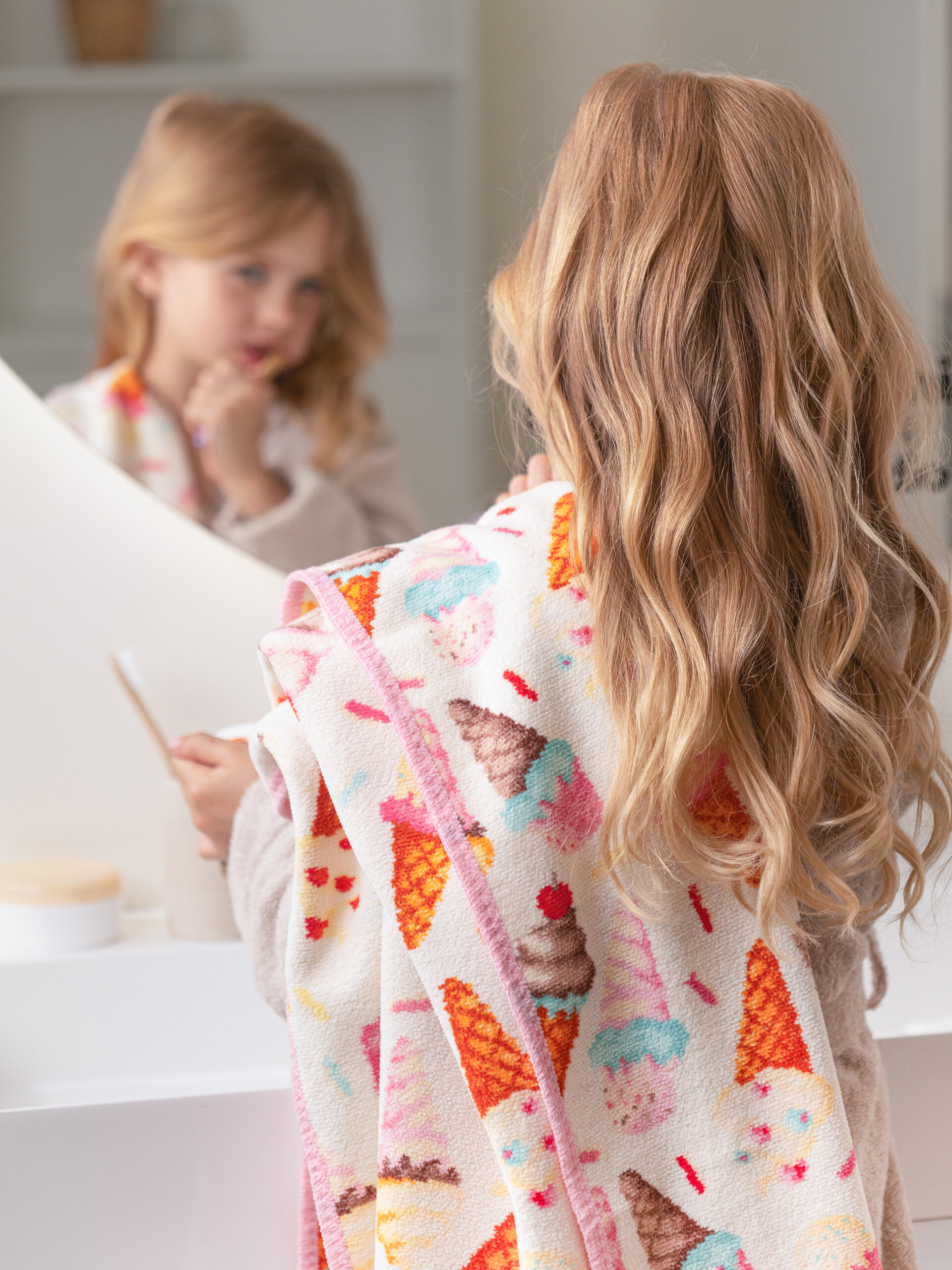Kind mit buntem Handtuch vorm Spiegel – Luxuriöses FEILER Handtuch der Kollektion SWEET SPRINKLES als Lifestyleaufnahme aus Original FEILER-Chenille, Made in Germany.