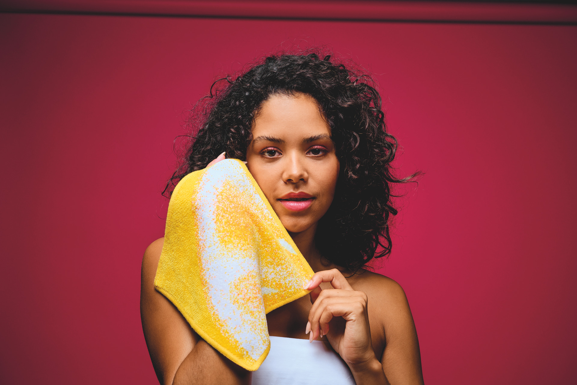 Gelbes Chenille-Handtuch auf Rosa Hintergrund – Luxuriöses FEILER Handtuch der Kollektion FRUITS als Lifestyleaufnahme aus Original FEILER-Chenille, Made in Germany.