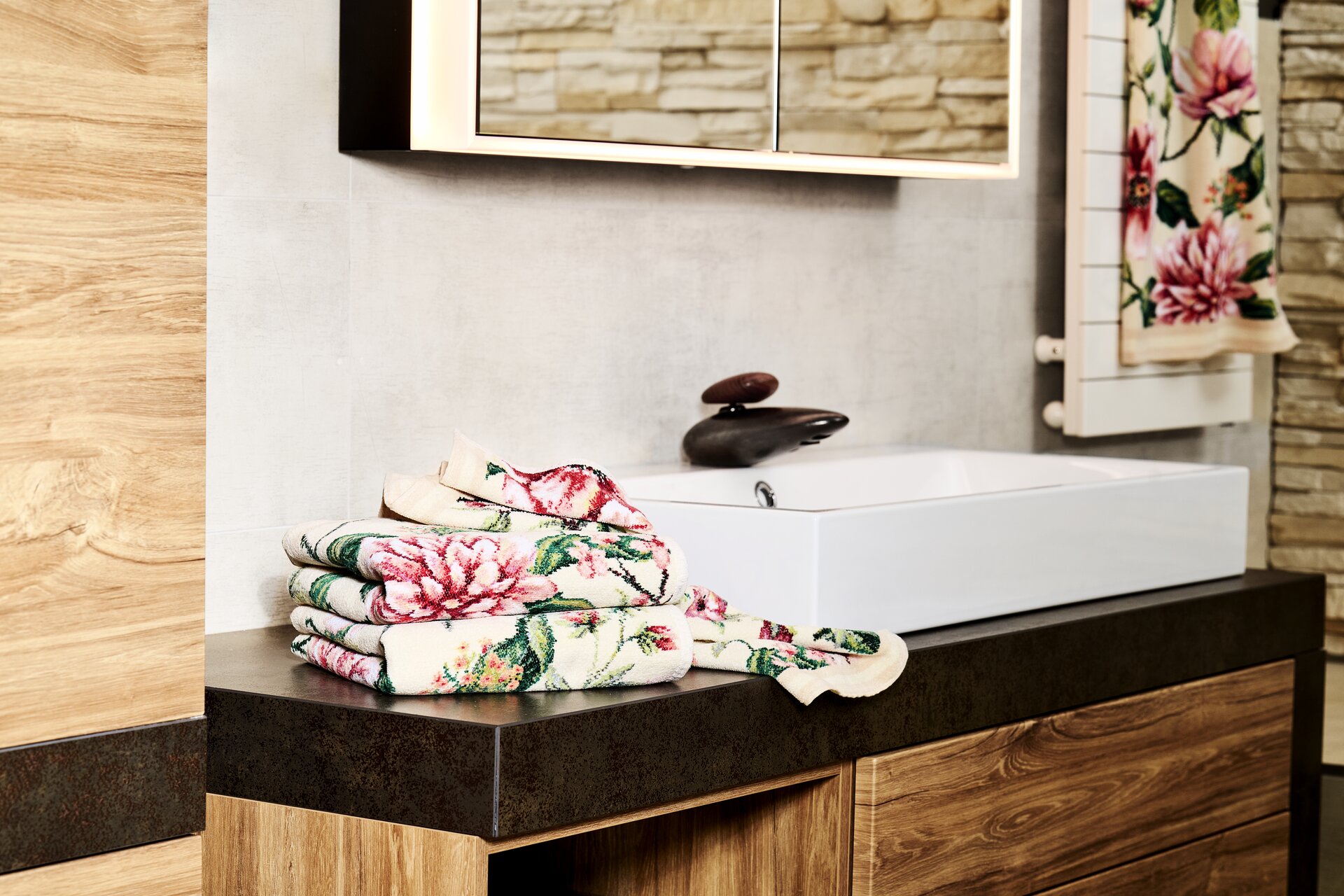 Blumendesign Handtuch auf Holzregal – Luxuriöses FEILER Handtuch der Kollektion EDEN als Lifestyleaufnahme aus Original FEILER-Chenille, Made in Germany.