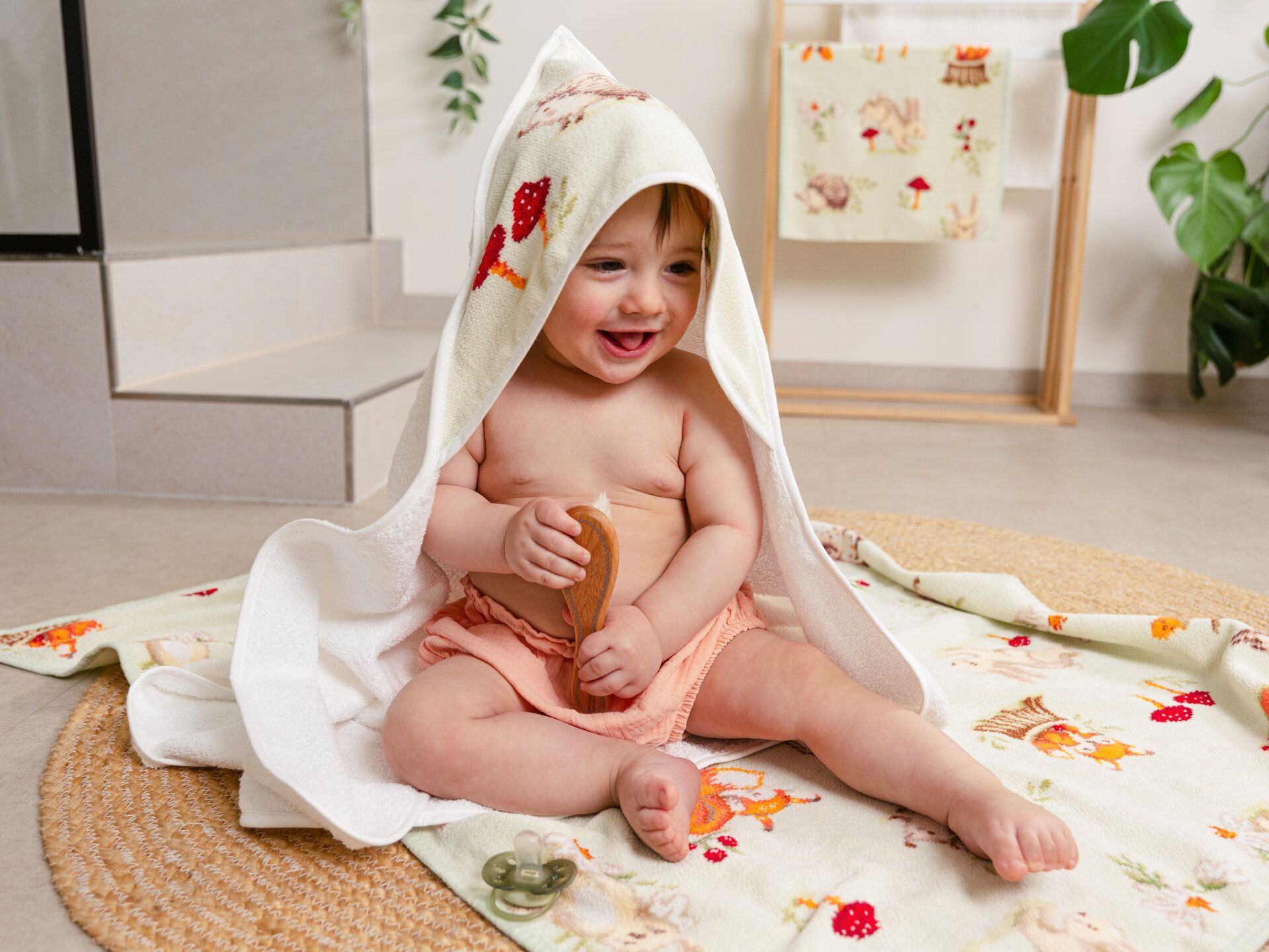 Baby unter Kapuzenhandtuch lachend – Luxuriöses FEILER Badetuch der Kollektion FOREST TALES als Lifestyleaufnahme aus Original FEILER-Chenille, Made in Germany.
