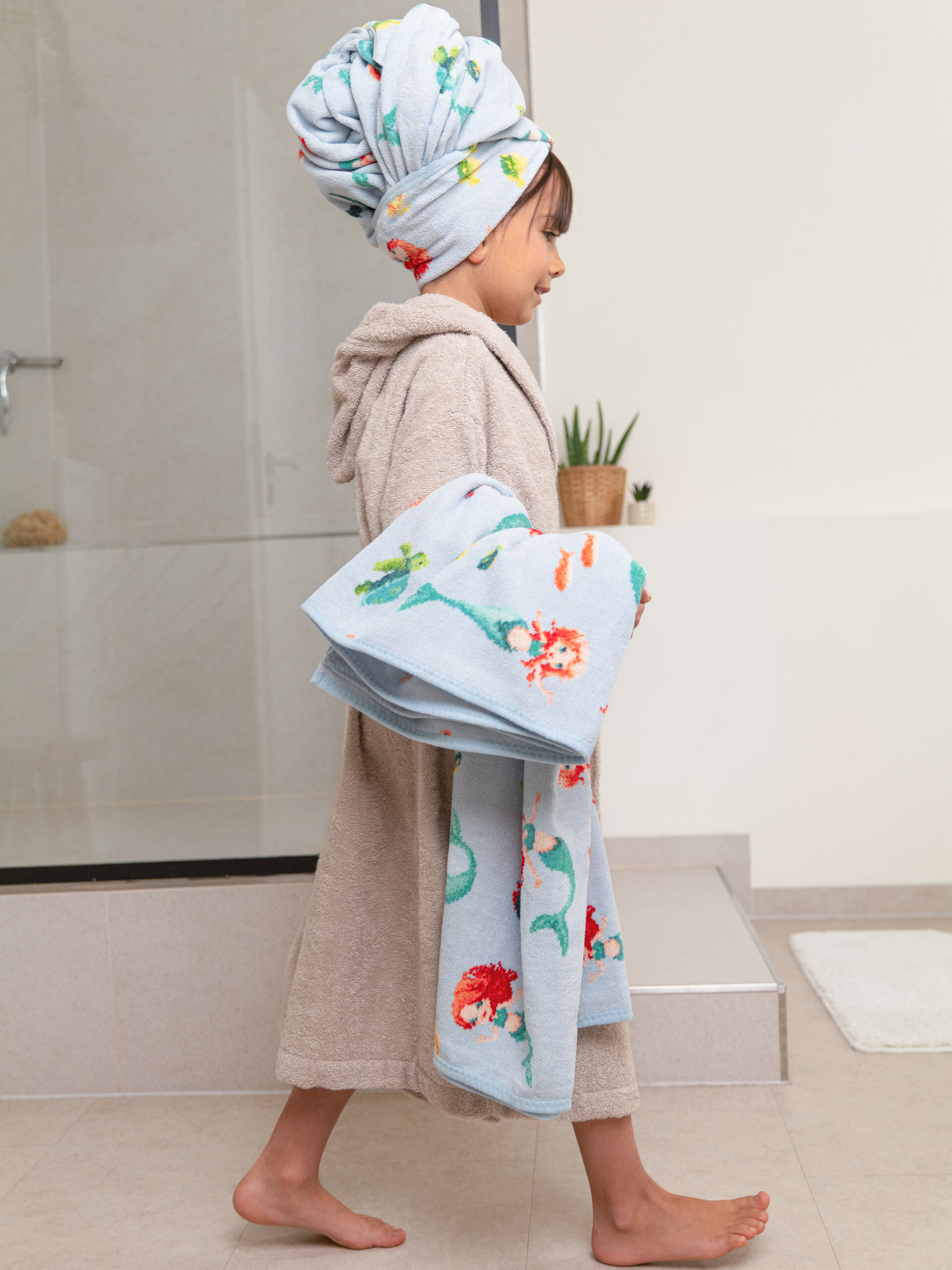 Kind mit flauschigem Meerjungfrauen Handtuch – Luxuriöses FEILER Handtuch der Kollektion MERMAID DREAMS als Lifestyleaufnahme aus Original FEILER-Chenille, Made in Germany.