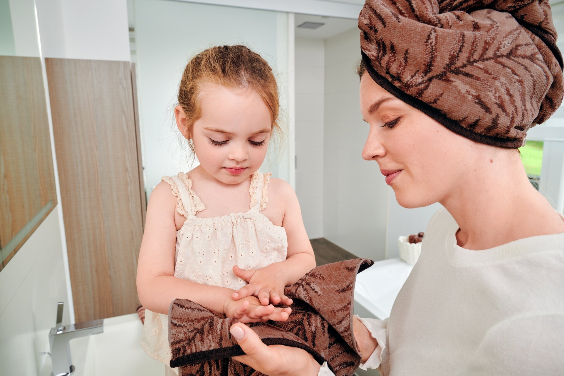 Lifestyle-Aufnahme mit Händen und einer Auswahl von FEILER OASIS NIGHTS Badtextilien und Accessoires aus Original FEILER-Chenille.