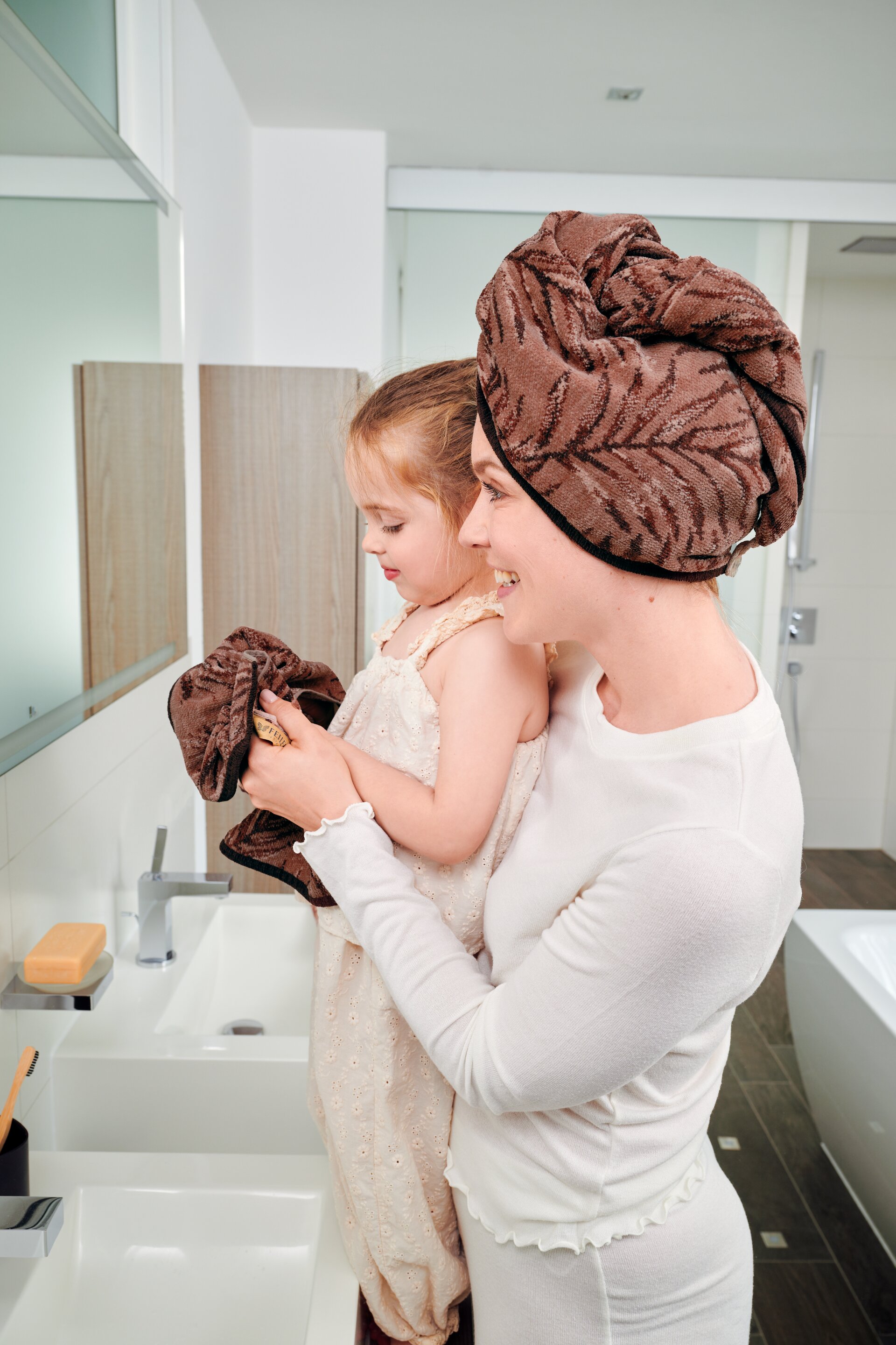 Second mirror lifestyle view featuring models and FEILER OASIS NIGHTS bath textiles in soft Original FEILER chenille.