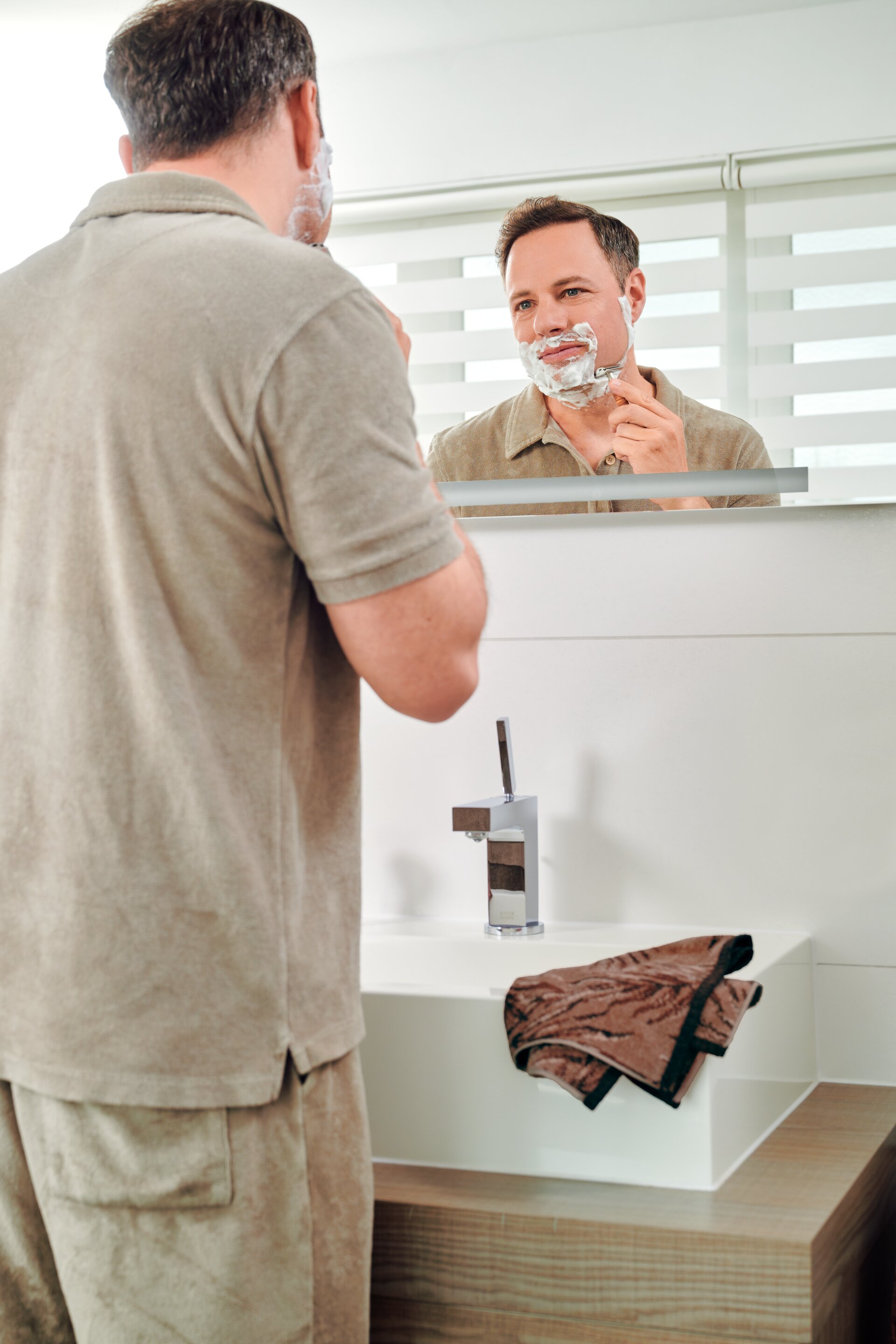 Grooming lifestyle scene with a model and FEILER OASIS NIGHTS bath textiles, showing Original FEILER chenille in a bathroom setting.