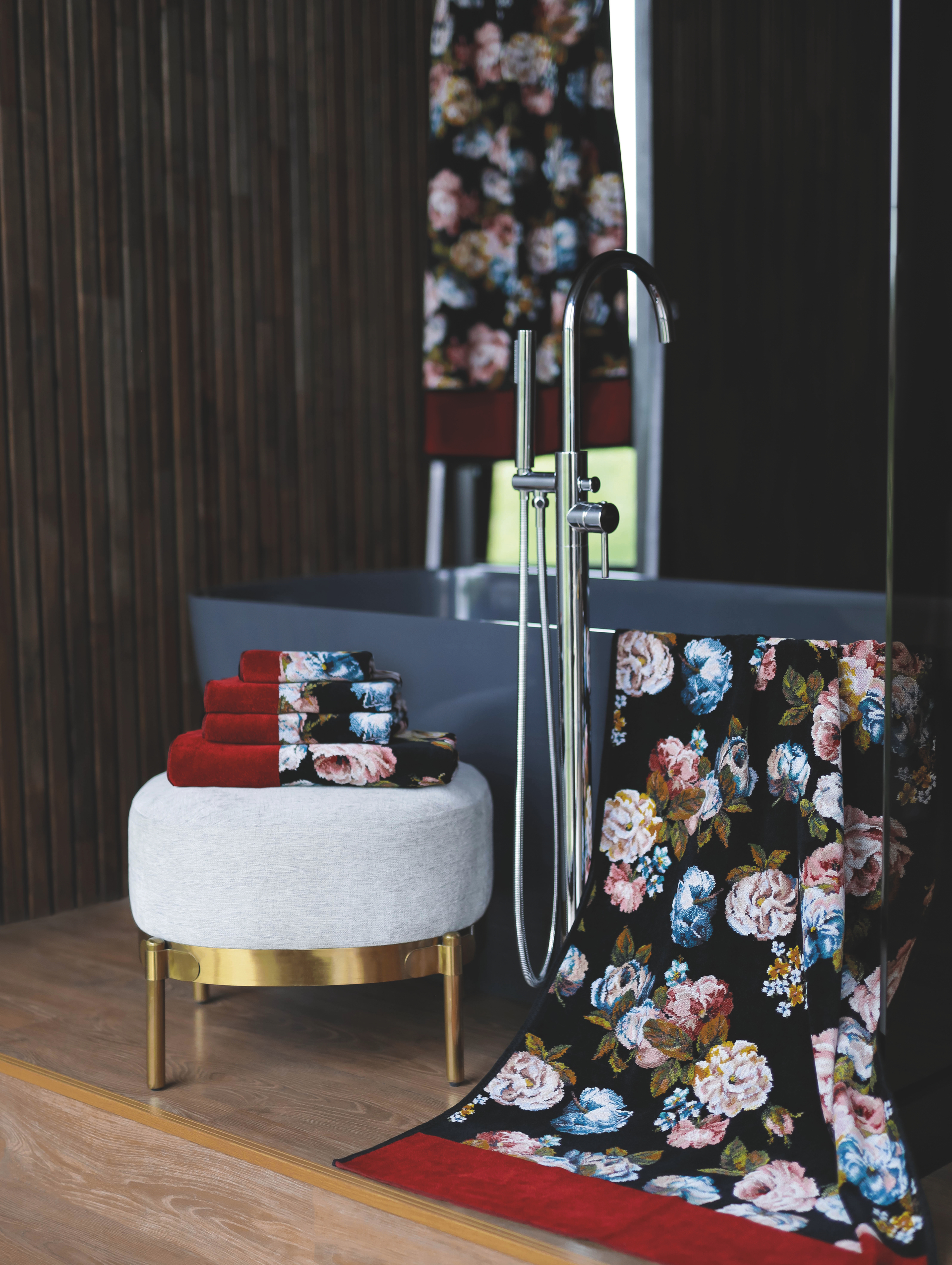 Luxurious bath textiles with a vibrant floral pattern on dark fabric, elegantly displayed in a modern bathroom.