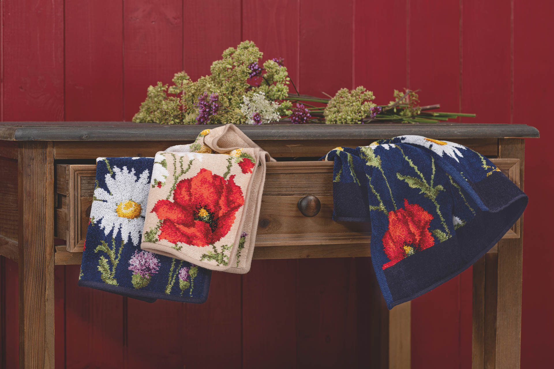 Florale Handtücher vor Holztisch – Luxuriöses FEILER Handtuch der Kollektion DAISY FIELD BLUE in Beige als Lifestyleaufnahme aus Original FEILER-Chenille, Made in Germany.