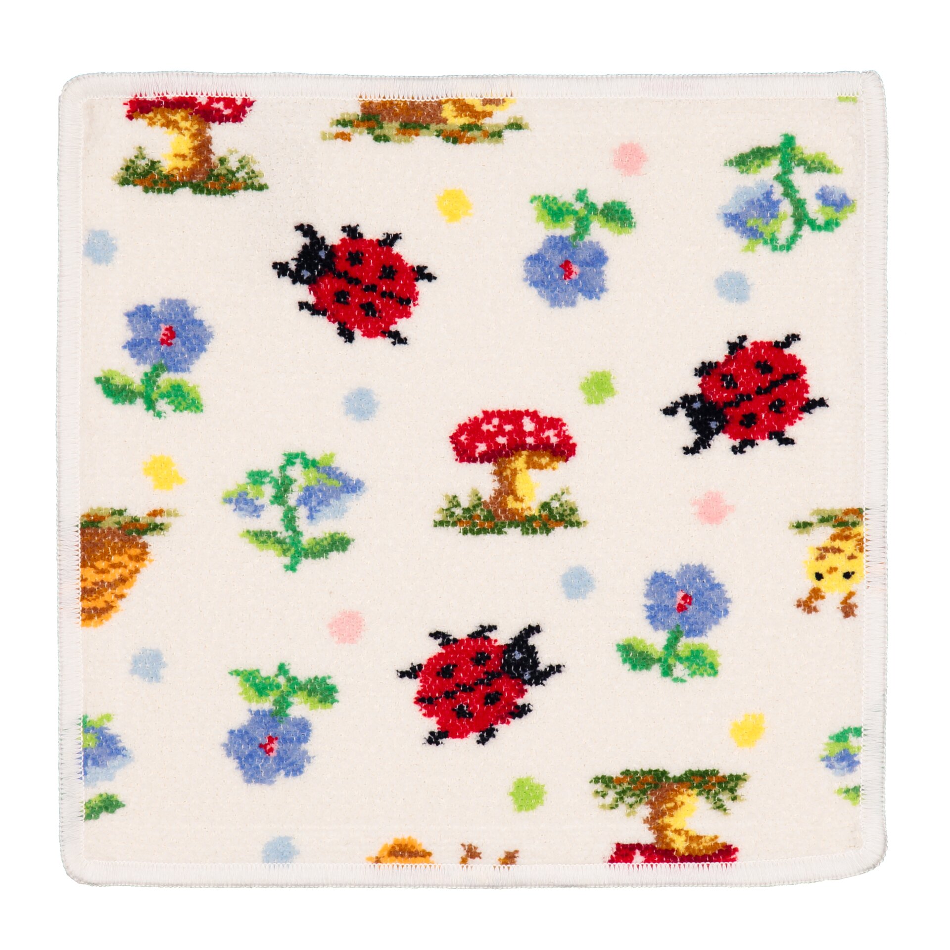 Colourful fabric square with red ladybirds, trees, mushrooms, and blue flowers on a cream background.