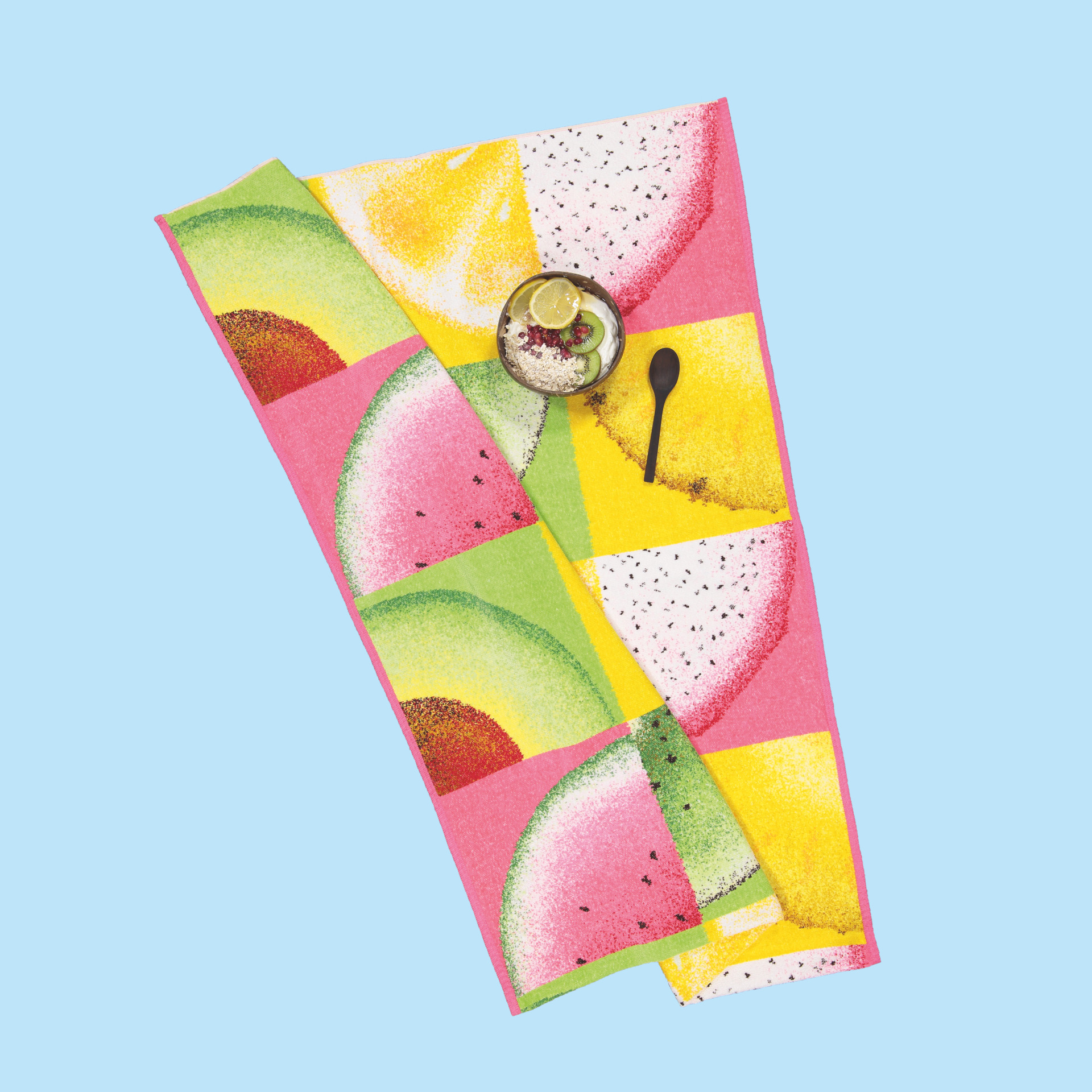 Buntes Chenille-Handtuch mit Frucht-Muster – Luxuriöses FEILER Strandtuch der Kollektion FRUITS FREISTELLER STRANDTUCH in Hellblau als Lifestyleaufnahme aus Original FEILER-Chenille, Made in Germany.