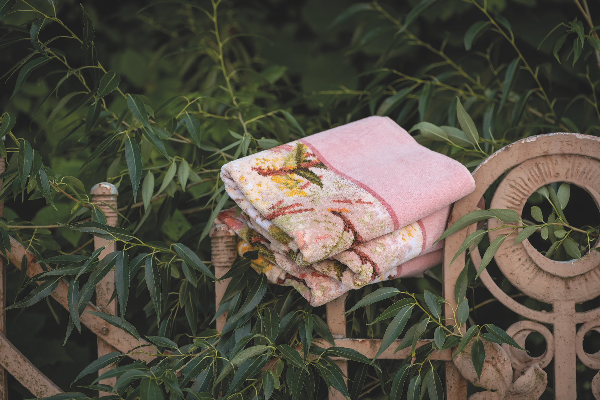 Folded pastel fabric with intricate floral and geometric patterns, draped over a decorative metal fence.