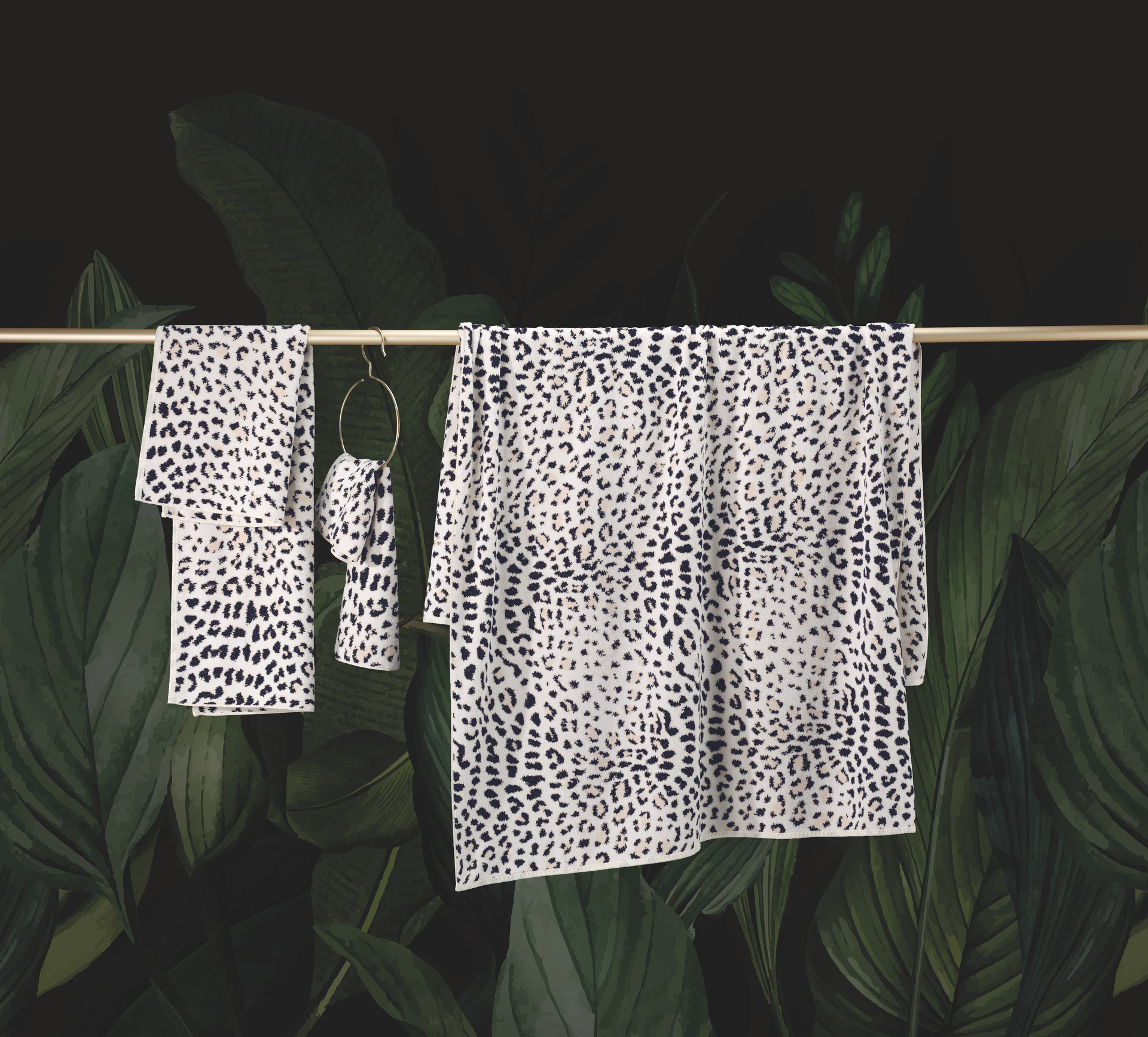 Textiles with a black and white spotted pattern against a lush green foliage background.