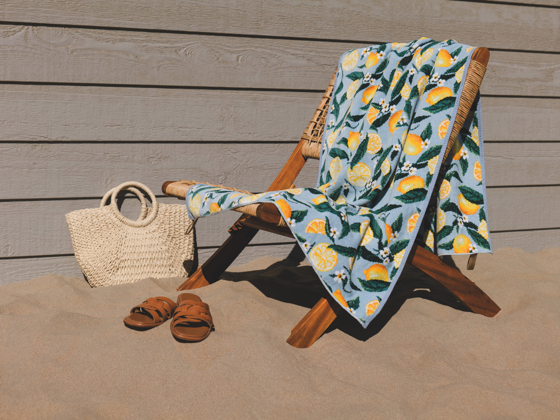 Luxus-Chenille-Handtuch mit Zitronenmotiv am Strand – Luxuriöses FEILER Handtuch der Kollektion LEMONS AND LEAVES als Lifestyleaufnahme aus Original FEILER-Chenille, Made in Germany.