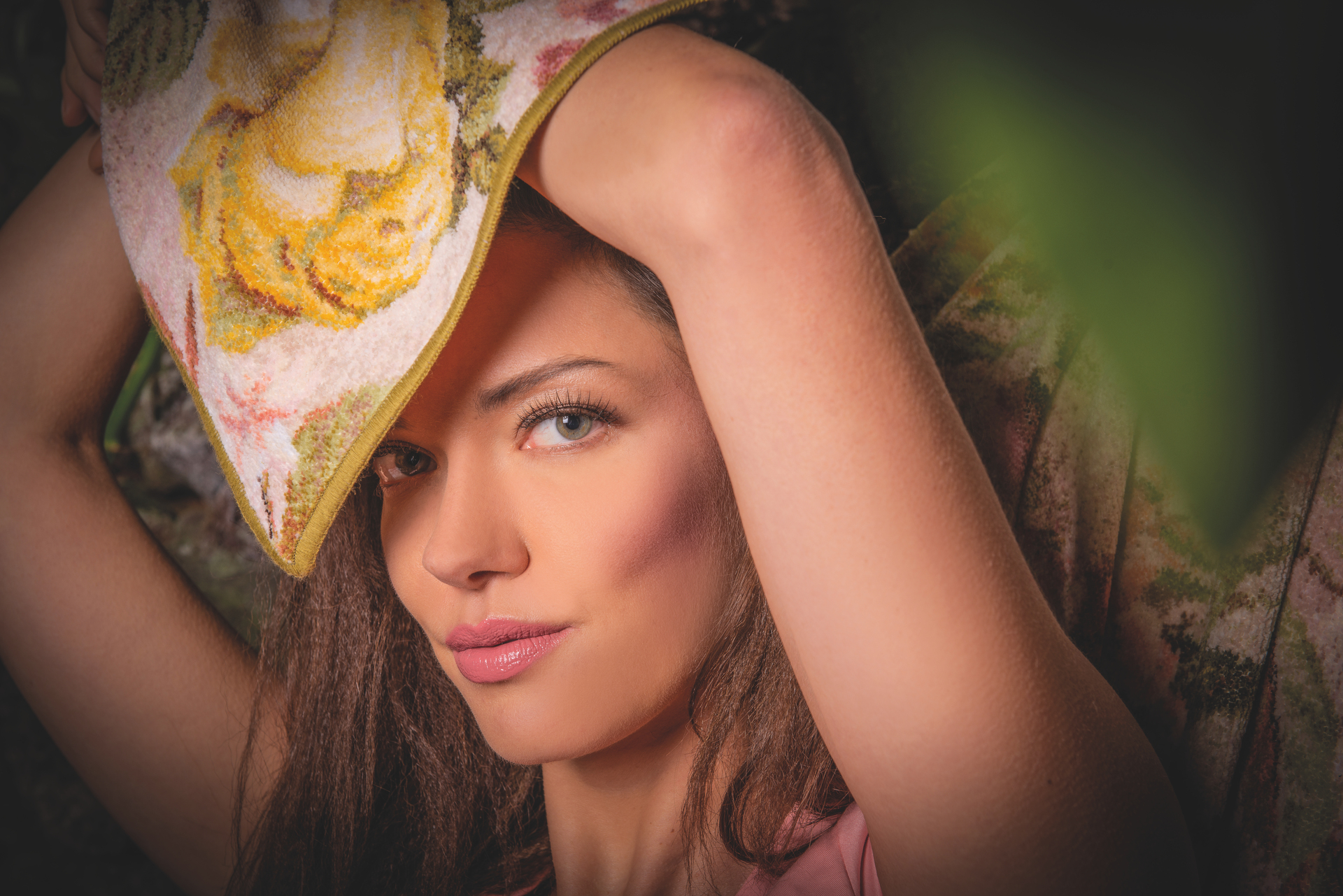 Adult woman with brown hair, holding a floral-patterned chenille textile, featuring yellow roses.