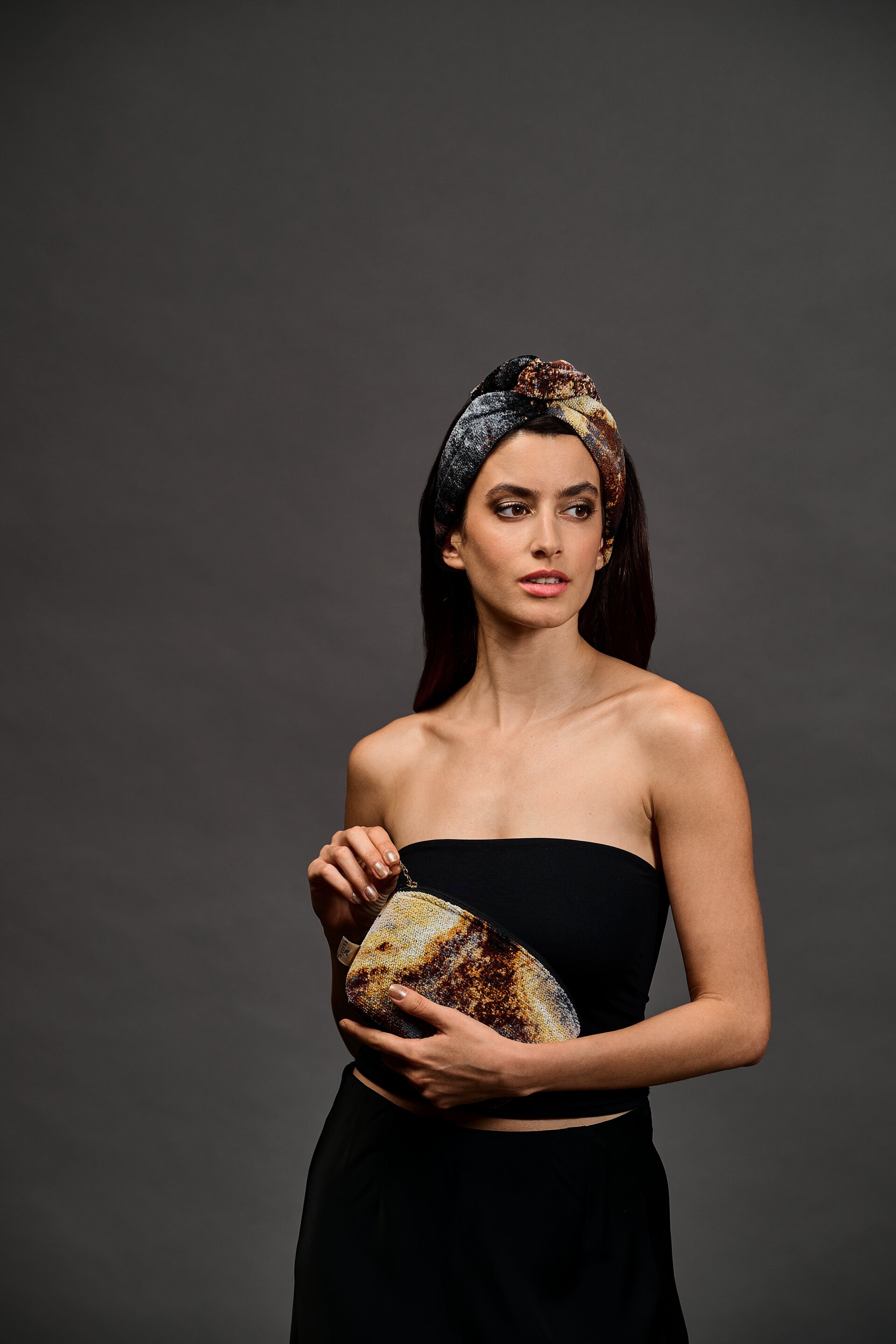 Frau mit gemustertem Stirnband und Tasche – Luxuriöse FEILER Tasche der Kollektion GOLDEN FRAGMENTS als Lifestyleaufnahme aus Original FEILER-Chenille, Made in Germany.