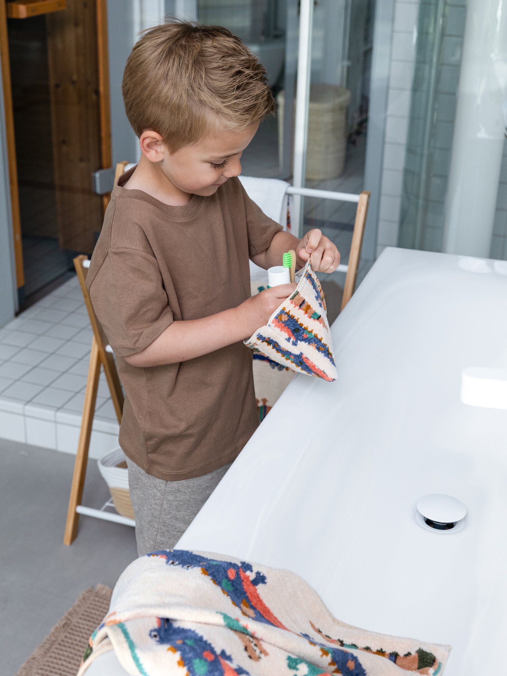 Lifestyle-Aufnahme mit FEILER KROKO Täschchen M10 und Pflegetuch aus Original FEILER-Chenille, von einem Model in den Händen gehalten.