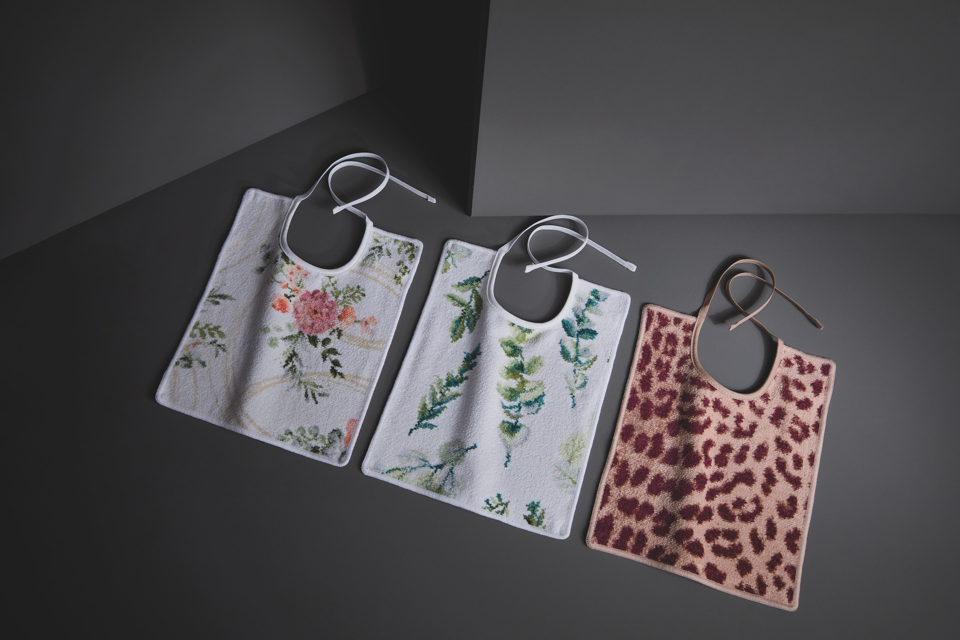 Drei gemusterte Chenille-Badtextilien – Luxuriöses FEILER Lätzchen der Kollektion GENTLE LEAVES WILD als Lifestyleaufnahme aus Original FEILER-Chenille, Made in Germany.