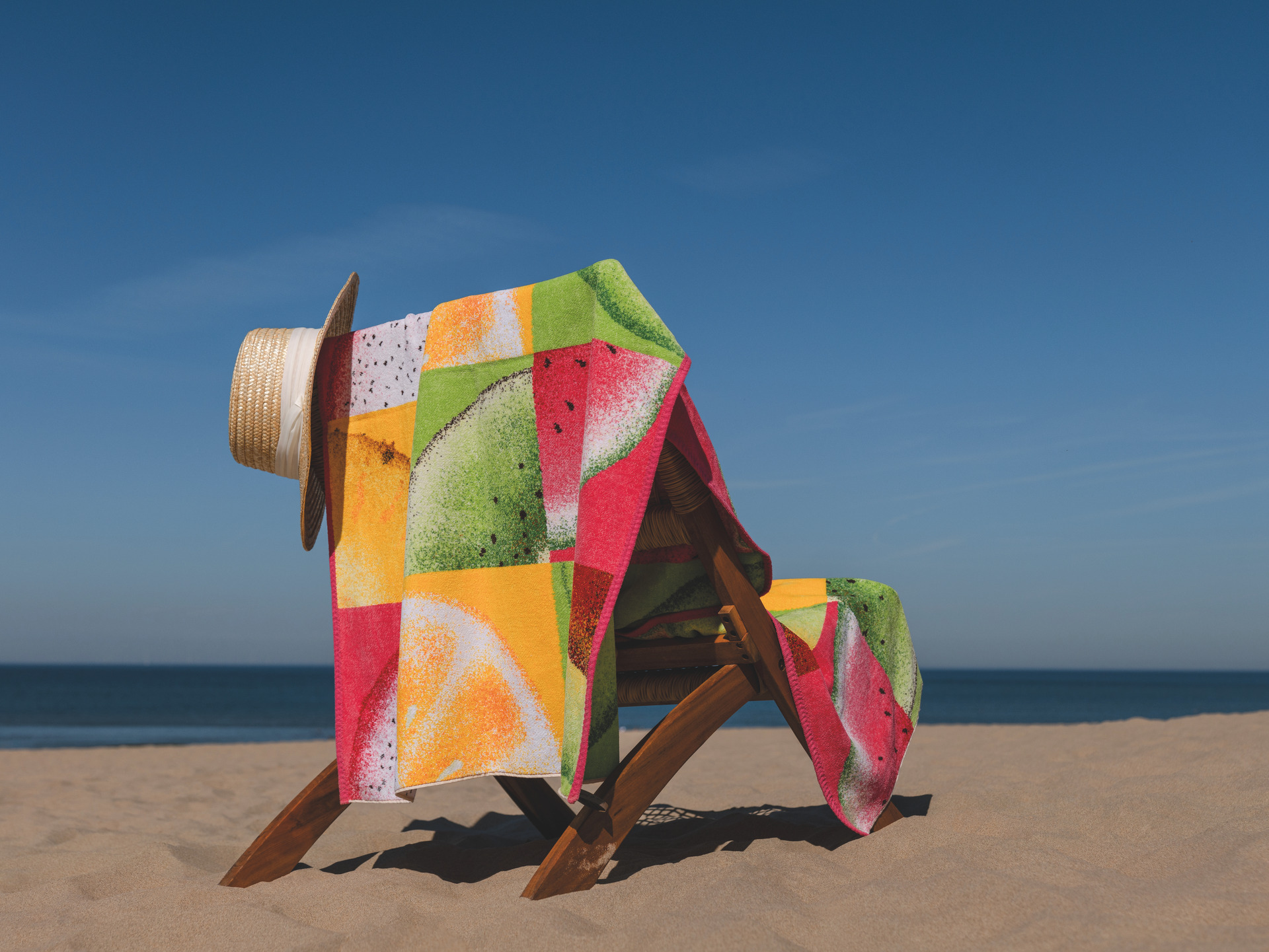 Buntes Strandtuch am Sandstrand – Luxuriöses FEILER Strandtuch der Kollektion FRUITS als Lifestyleaufnahme aus Original FEILER-Chenille, Made in Germany.
