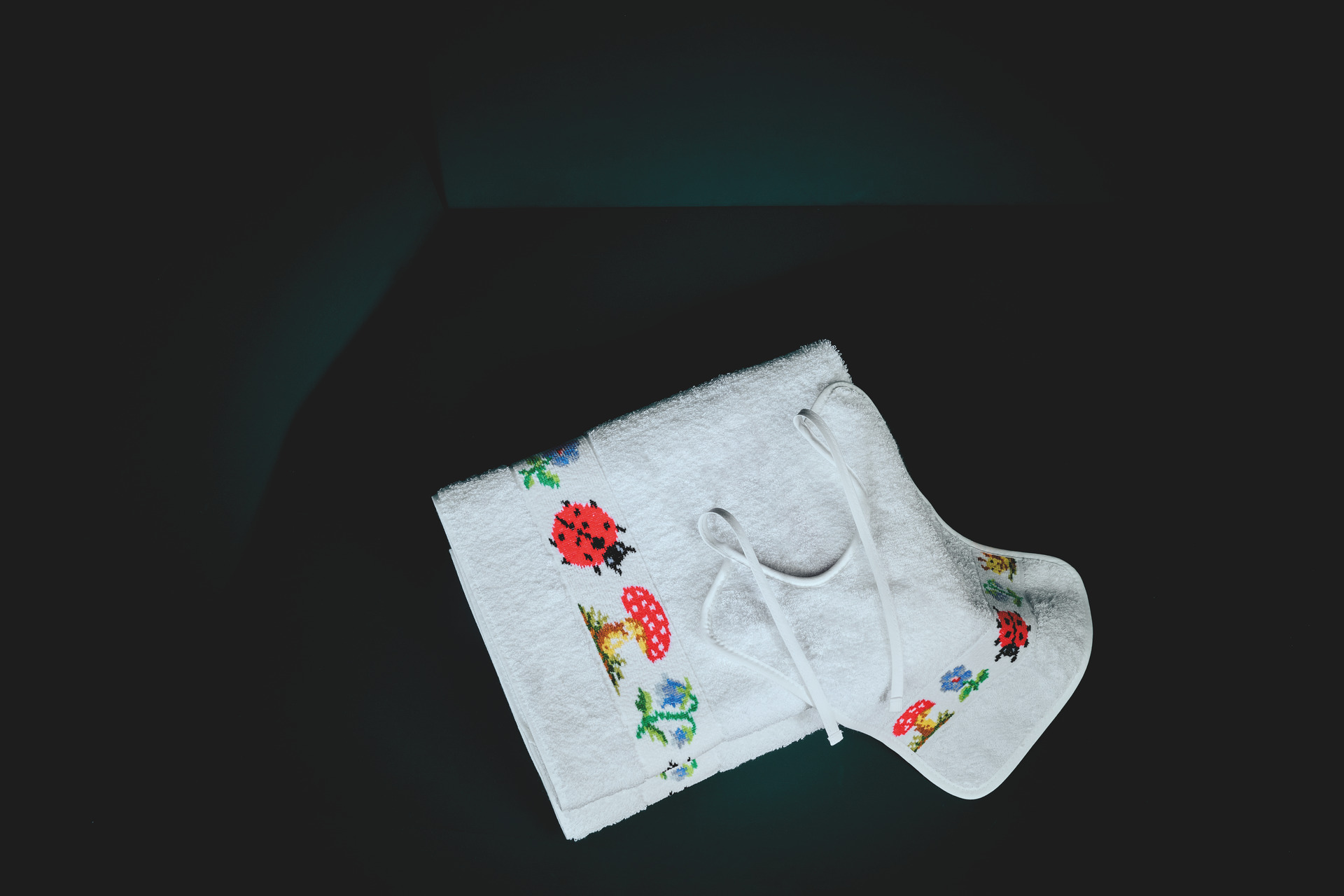 White textile with ladybird and mushroom patterns on dark background.