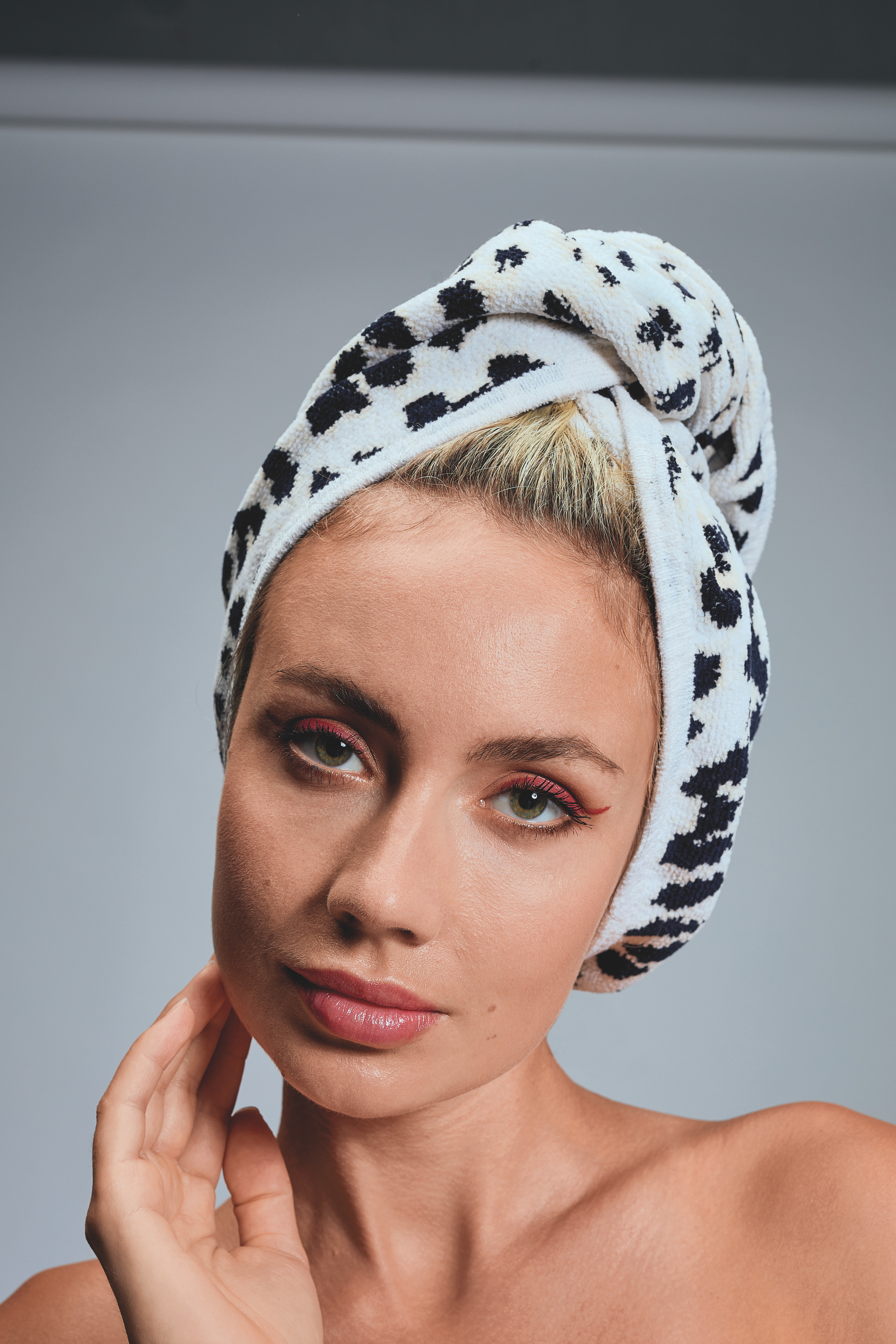Adult woman with a towel wrapped around her head, featuring a black and white floral pattern.