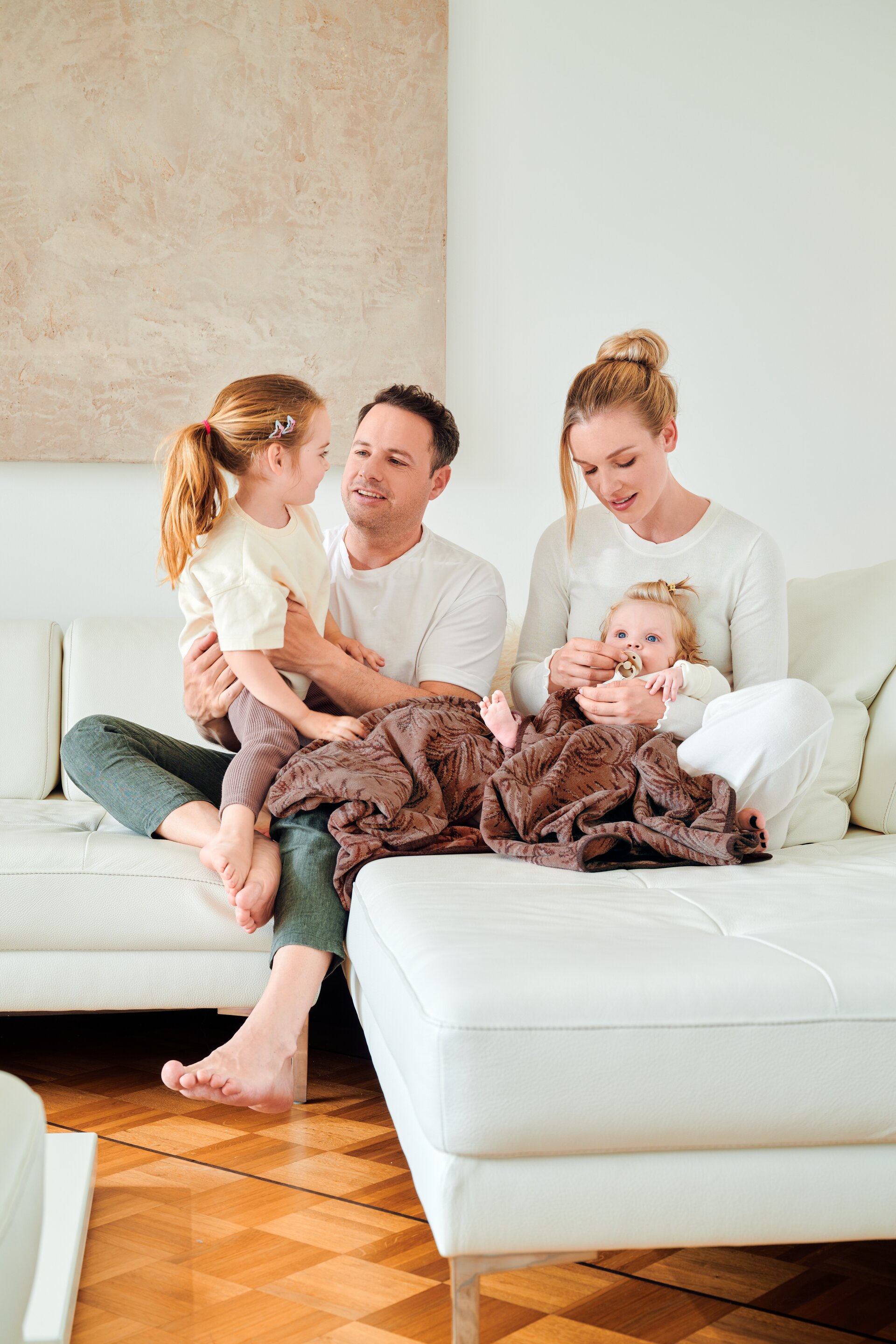 Sofa lifestyle image with models and coordinated FEILER OASIS NIGHTS home textiles made from Original FEILER chenille in Germany.