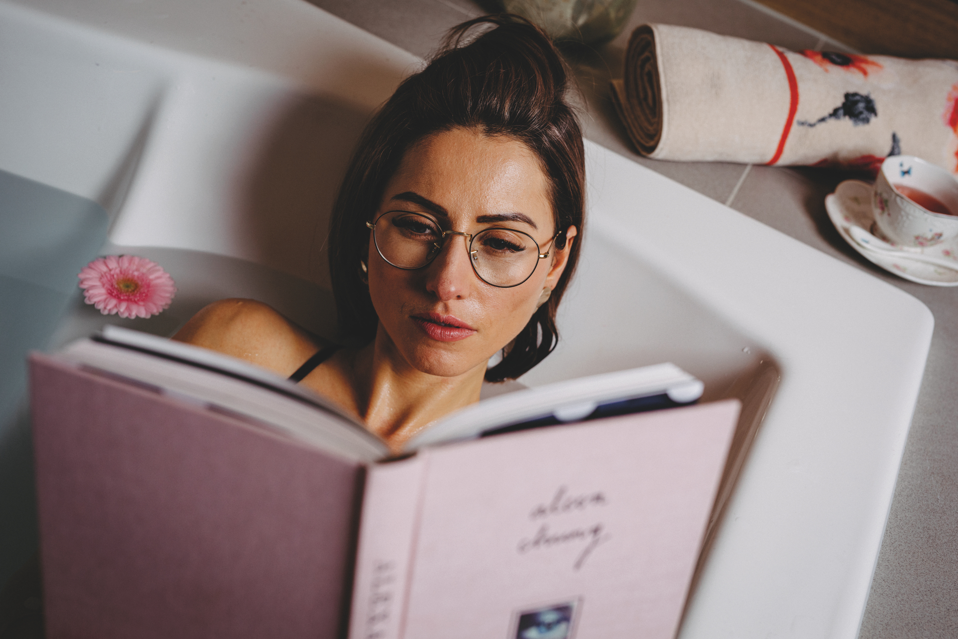 Entspannung in der Badewanne mit einem Buch – Luxuriöses FEILER Handtuch der Kollektion KLATSCHMOHN als Lifestyleaufnahme aus Original FEILER-Chenille, Made in Germany.