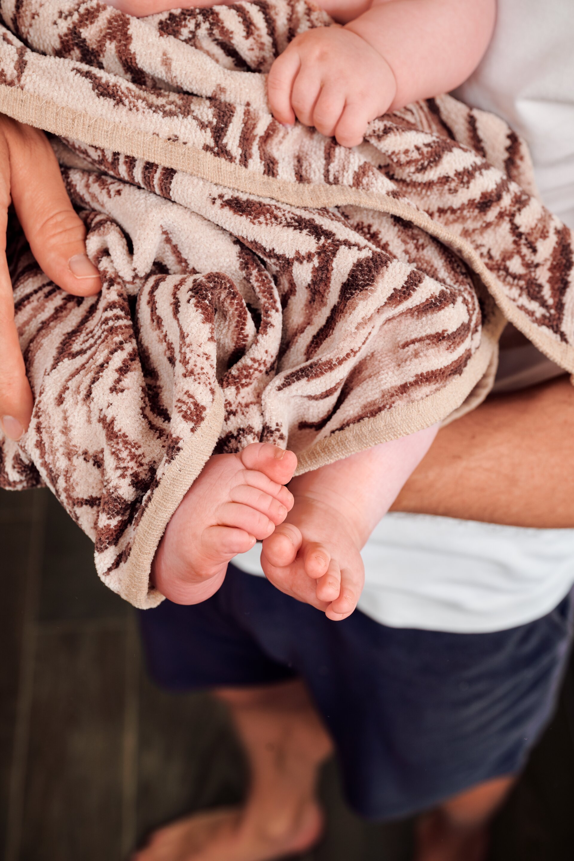 Lifestyle detail of FEILER DESERT PALMS baby textiles shown with a child's feet, highlighting the soft Original FEILER chenille surface.