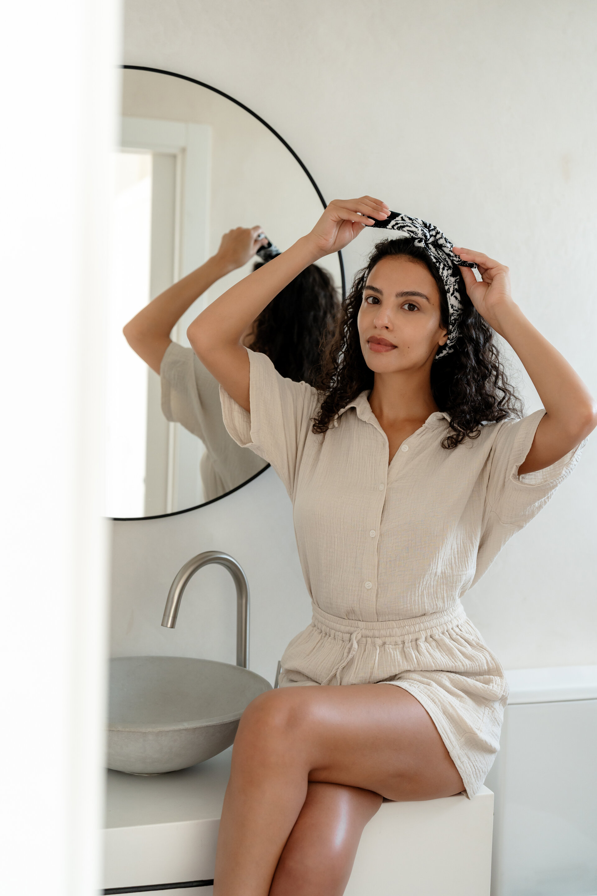 Frau im Badezimmer mit modischem Haarband – Luxuriöses FEILER Handtuch der Kollektion JUNGLE als Lifestyleaufnahme aus Original FEILER-Chenille, Made in Germany.