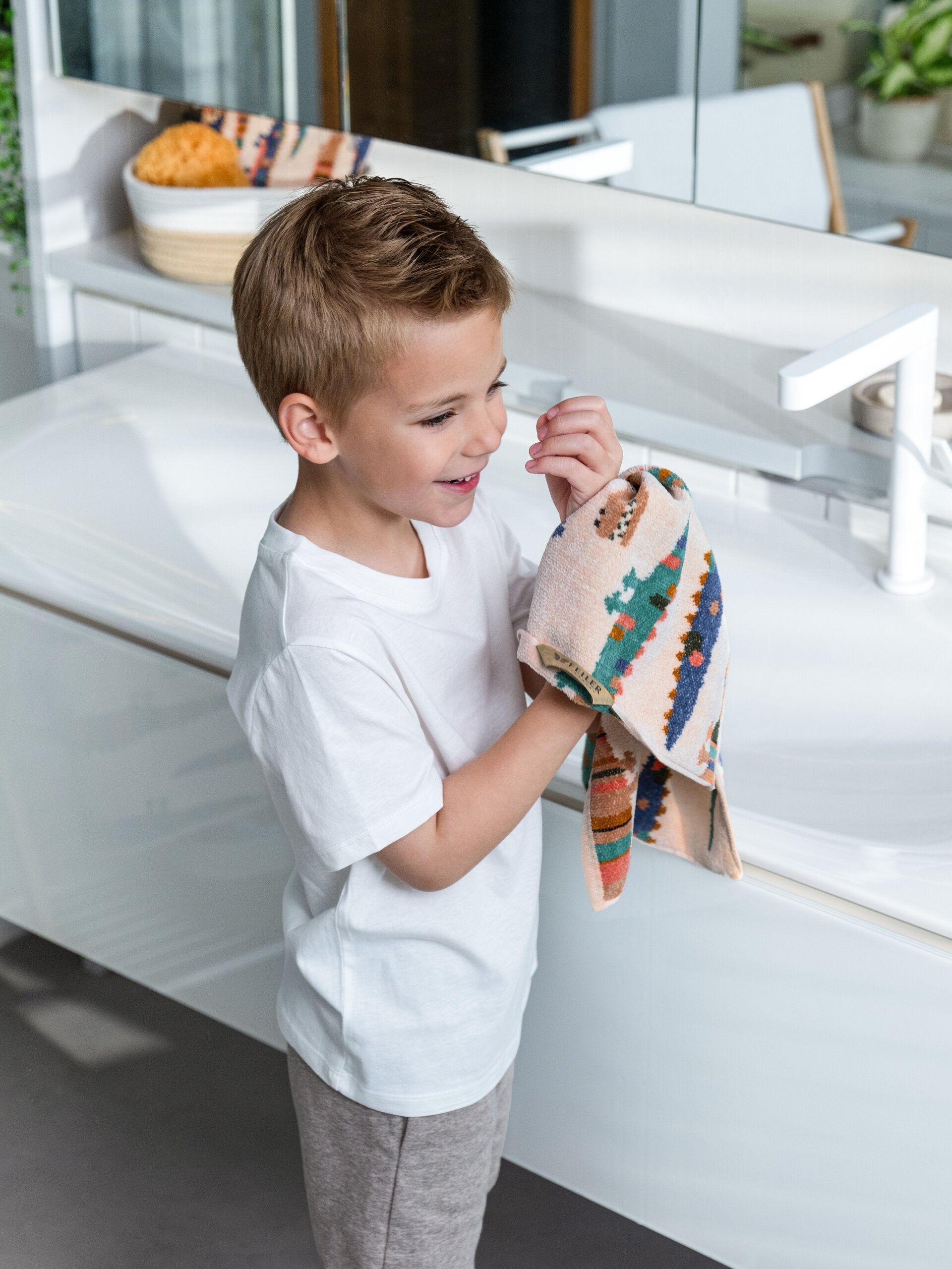 Lifestyle-Aufnahme des FEILER KROKO Kinder-Handtuchs, Größe 37 × 50 cm, aus Original FEILER-Chenille beim Abtrocknen einer Hand.