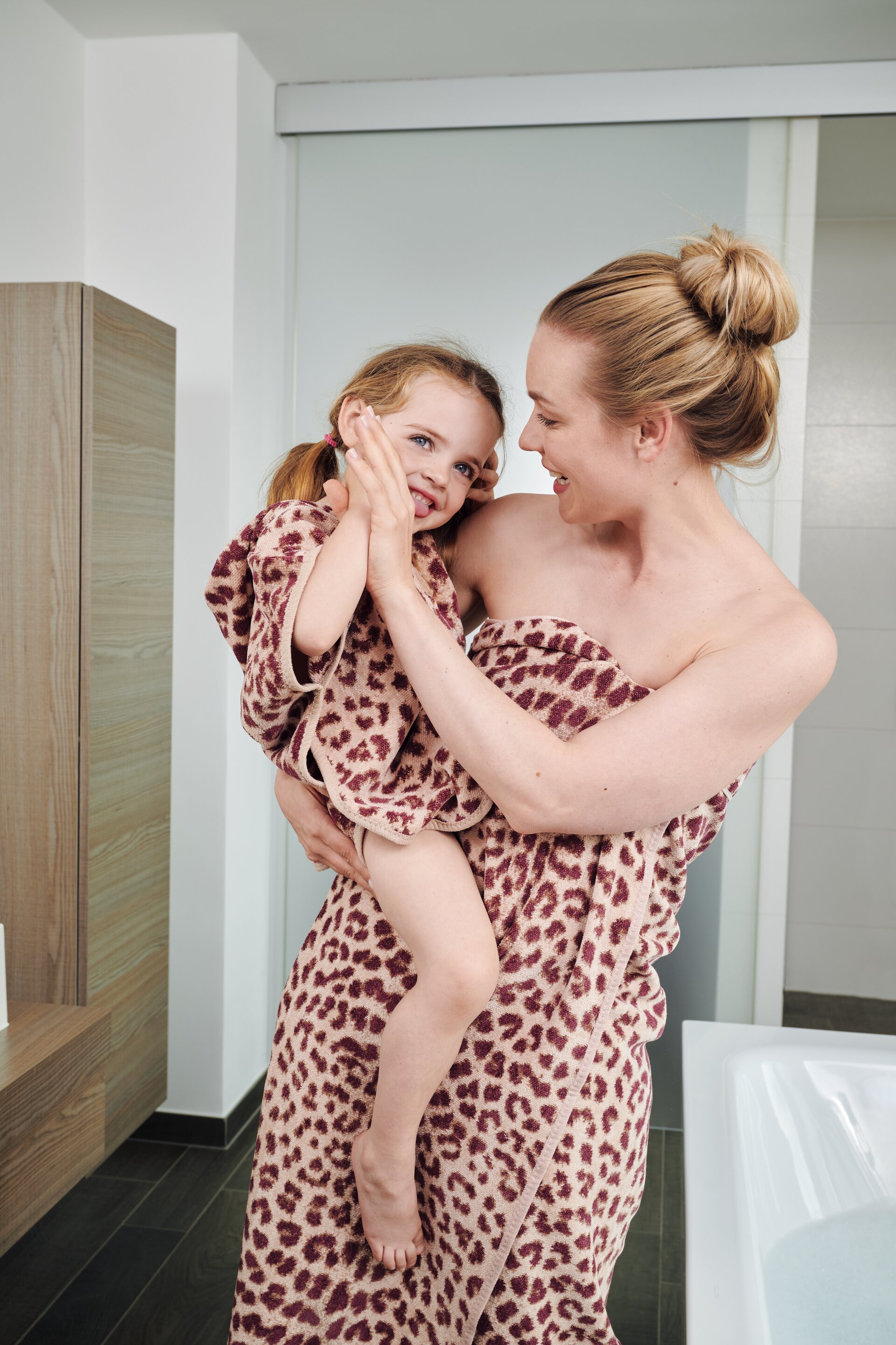 Erste Lifestyle-Aufnahme mit Models und ausgewählten FEILER WILD LEO Badtextilien aus Original FEILER-Chenille in einem Badezimmer.
