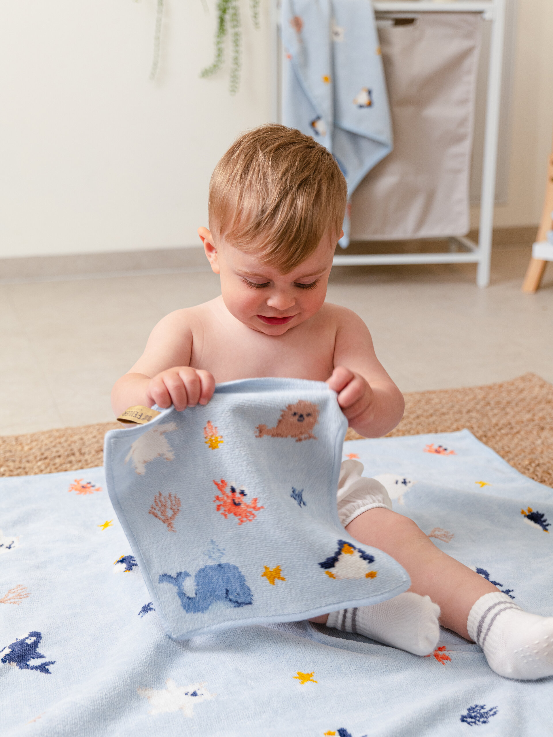 Kuscheliges Baby in Chenille-Decke – Luxuriöse FEILER Decke der Kollektion POLAR FRIENDS als Lifestyleaufnahme aus Original FEILER-Chenille, Made in Germany.