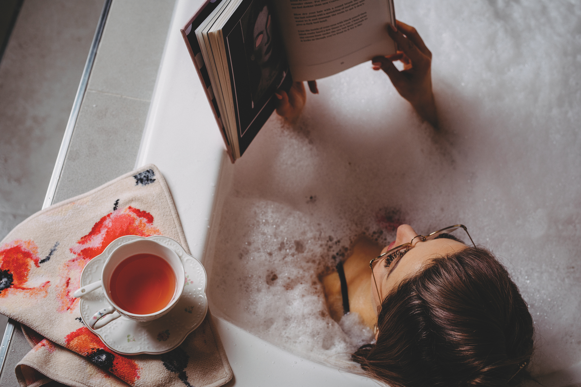 Entspannen in der Badewanne mit Buch – Luxuriöses FEILER Handtuch der Kollektion KLATSCHMOHN als Lifestyleaufnahme aus Original FEILER-Chenille, Made in Germany.